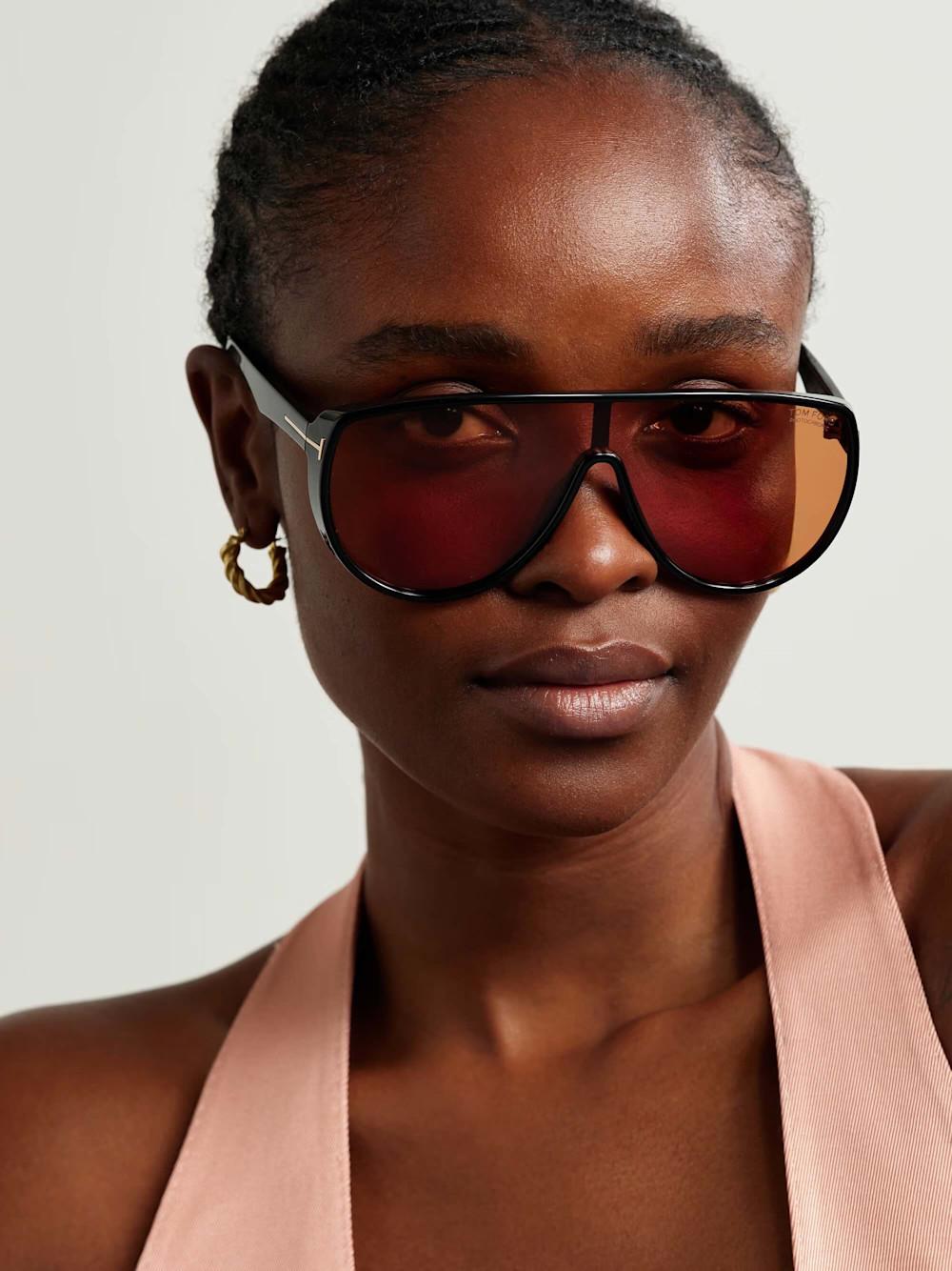 Woman wearing Tom Ford oversized shield sunglasses with rose-tinted photochromic lenses and black acetate frame β available at Elevate Vision Care in Markham